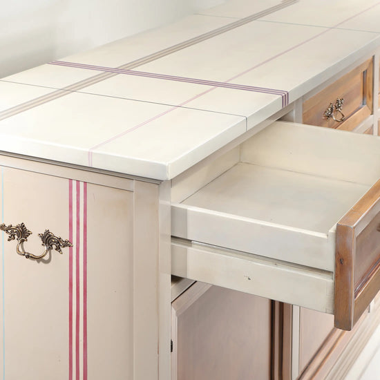 Cajón abierto del aparador Amara y detalle del sobre marfil con líneas decorativas.