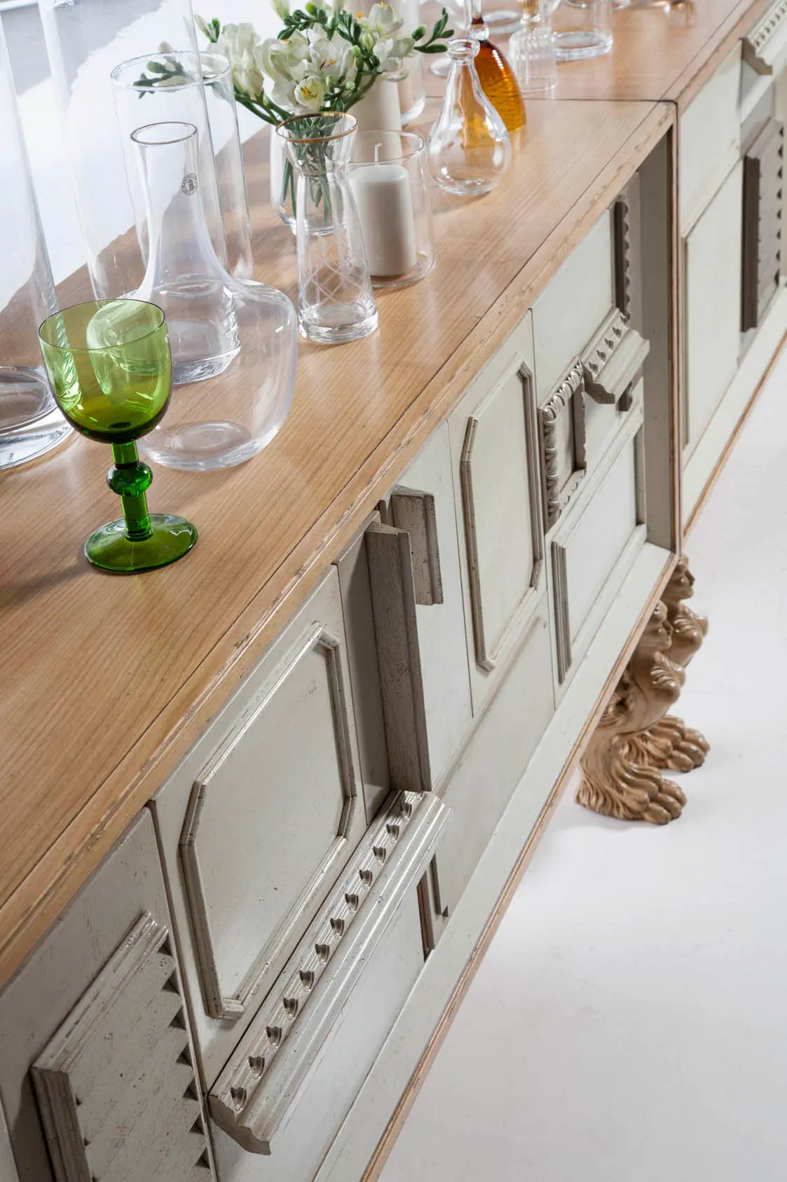 Aparador de madera Lamassu con puertas decoradas y patas talladas en un salón luminoso