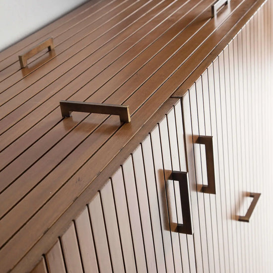 Armario auxiliar Tauro con puertas de lamas verticales y tiradores decorativos.