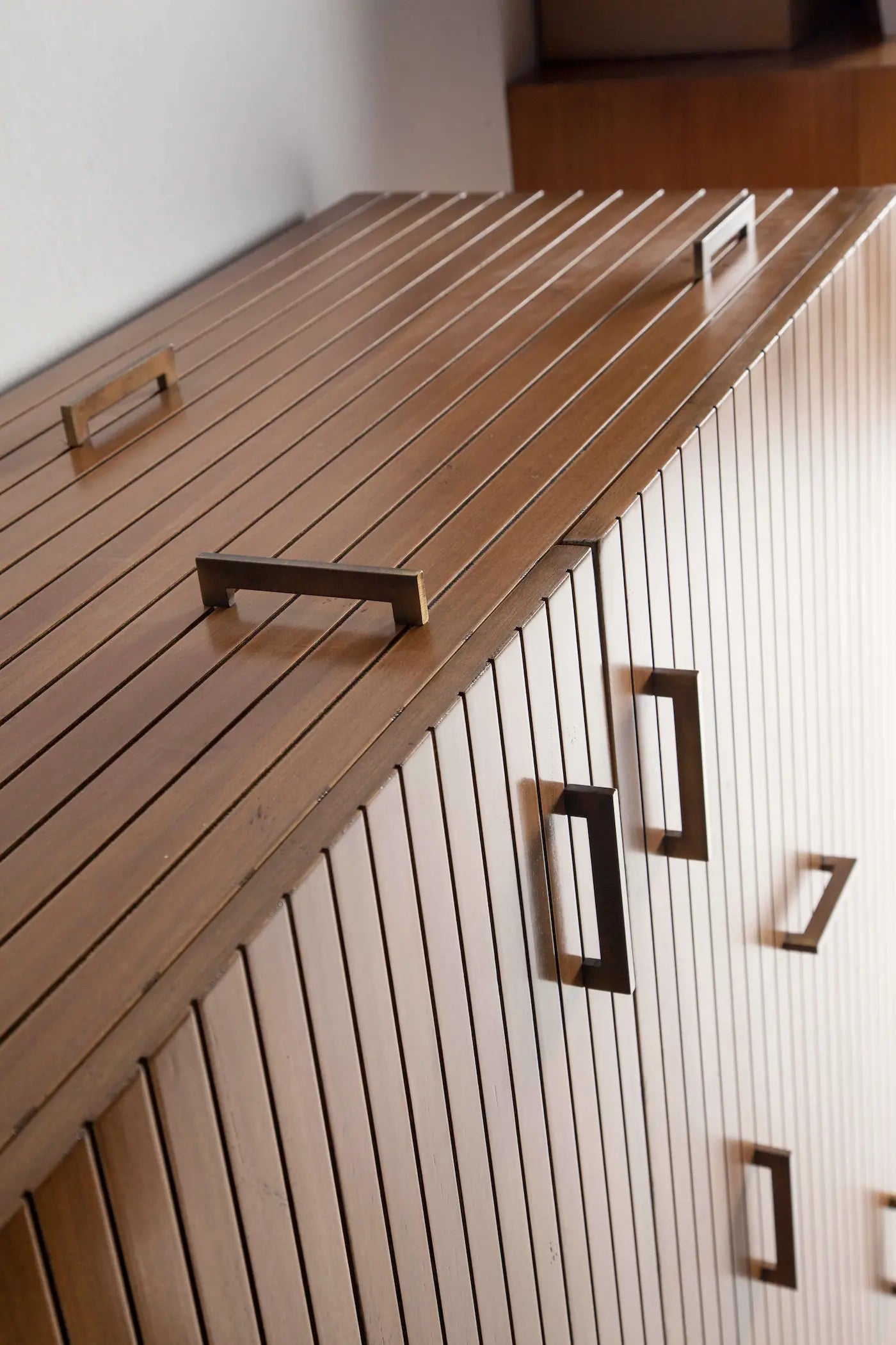 Armario auxiliar Tauro con puertas de lamas verticales y tiradores decorativos.