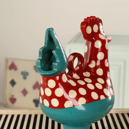 Detalle del Botijo Galla de cerámica con forma de gallina, cuerpo rojo con lunares blancos y cola azul turquesa esmaltada.