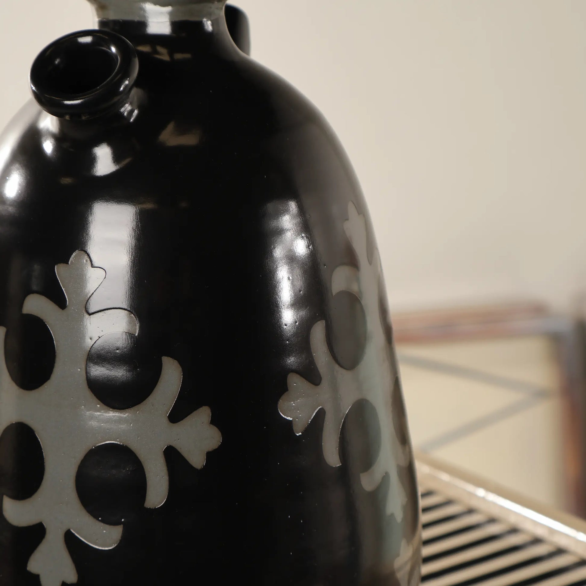 Detalle del cuerpo negro brillante del Botijo Ovum con motivos geométricos claros y acabado cerámico esmaltado.