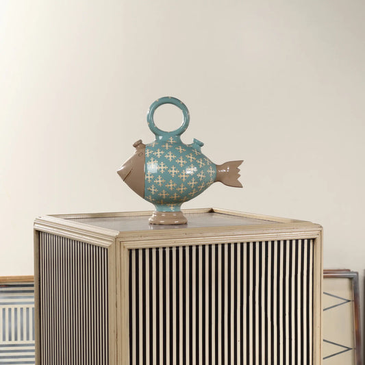 Botijo Poisson de cerámica colocado sobre un mueble decorativo de rayas, como pieza original para salones o recibidores.
