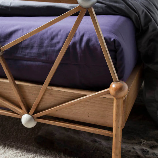 Detalle del piecero de la Cama Átomos con uniones geométricas, esferas decorativas y acabado artesanal.