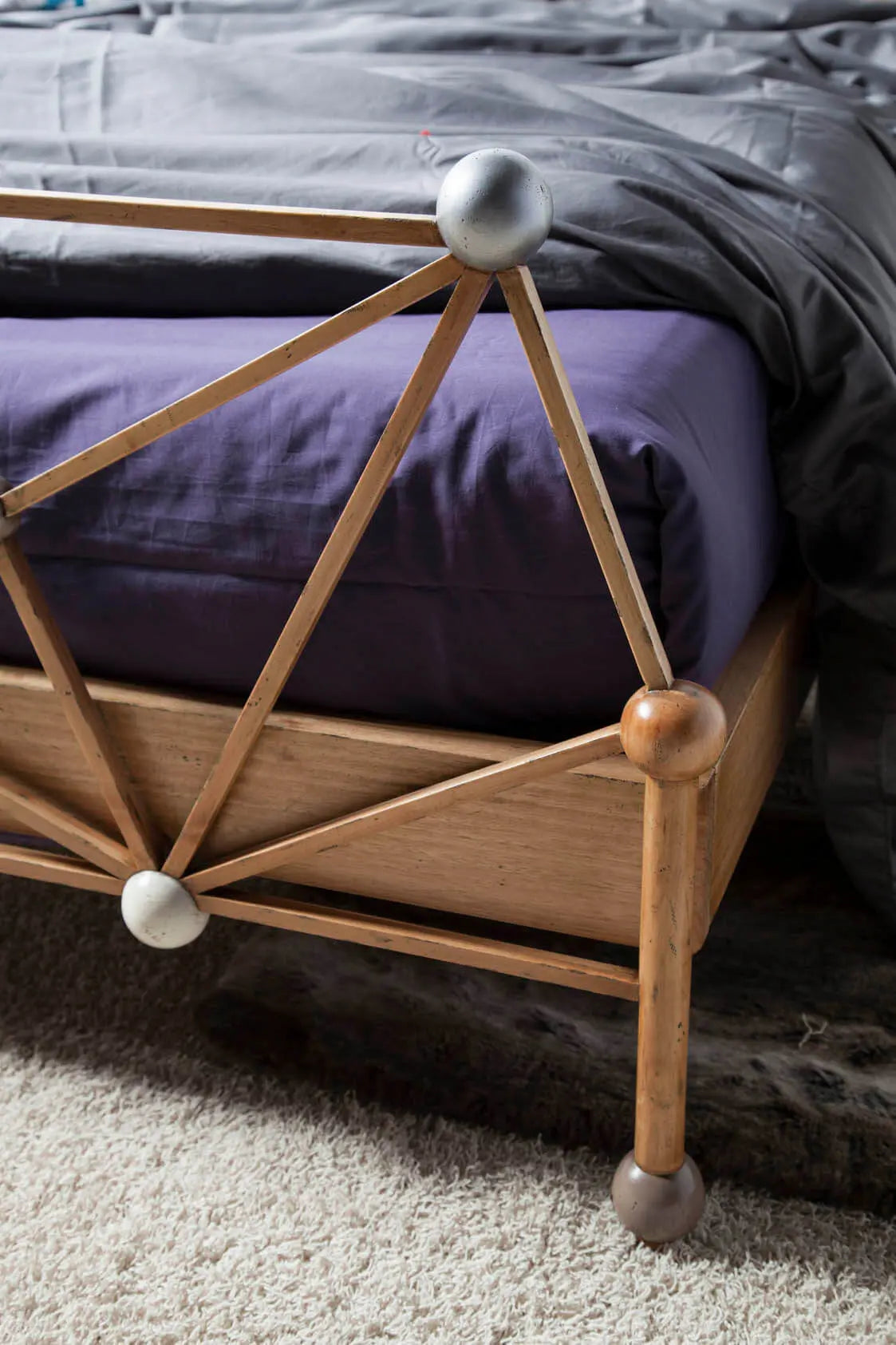 Detalle del piecero de la Cama Átomos con uniones geométricas, esferas decorativas y acabado artesanal.