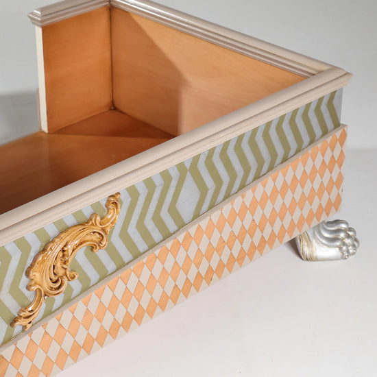 Detalle lateral de la cama para perro Casita Colette con greca en zigzag y aplique ornamental dorado.