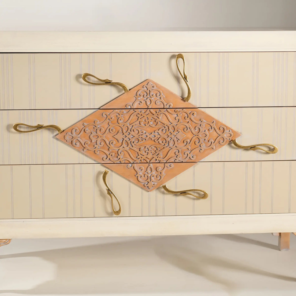 Detalle frontal de la cómoda Cait con motivo ornamental y tiradores escultóricos.