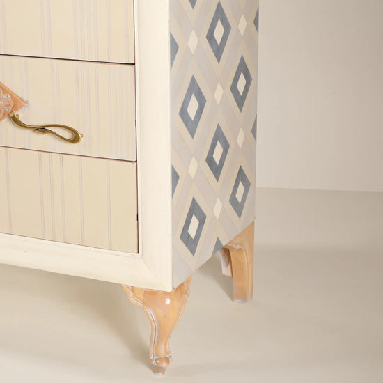 Detalle lateral de la cómoda Cait con diseño geométrico y patas de formas clásicas.