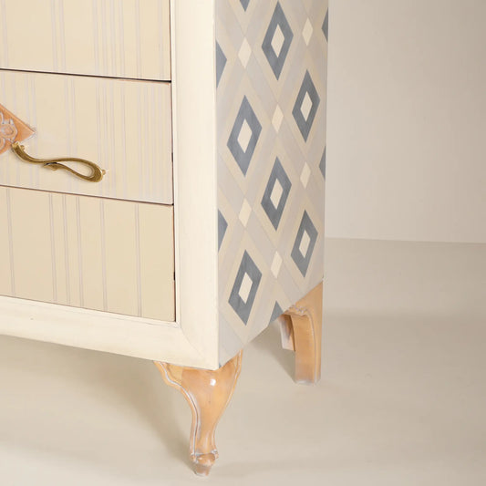 Detalle lateral de la cómoda Cait con diseño geométrico y patas de formas clásicas.