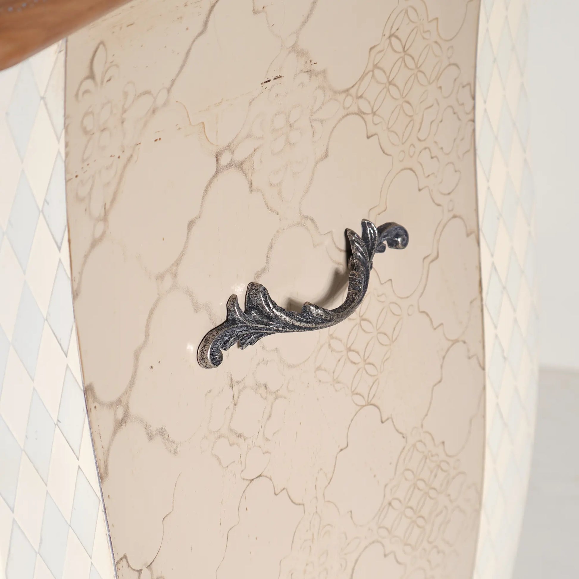 Lateral de la Cómoda Terilia con dibujo decorativo y tirador metálico de inspiración vegetal.