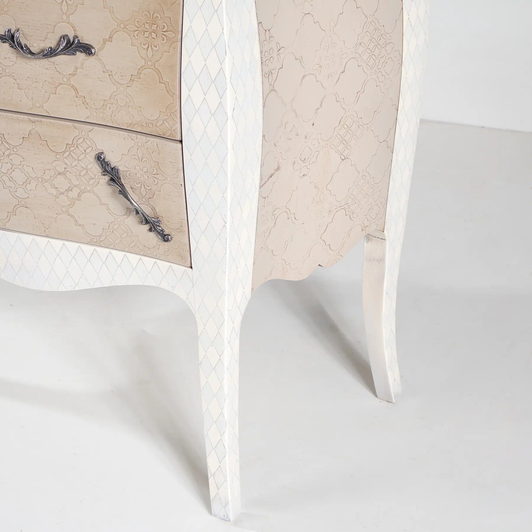 Detalle de las patas curvas de la Cómoda Terilia con acabado blanco marfil y decoración geométrica.