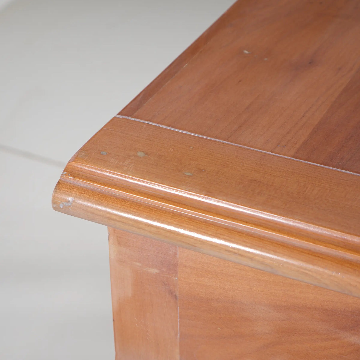 Detalle del tablero superior de la consola Araya, con veta visible y borde moldurado.