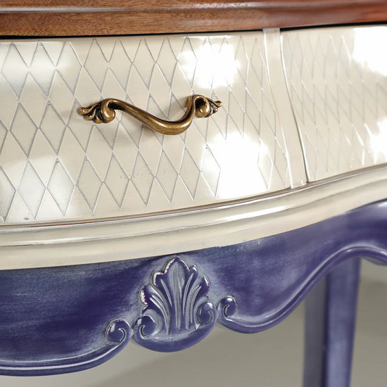Tirador metálico ornamental sobre cajón crema de la consola Charme.
