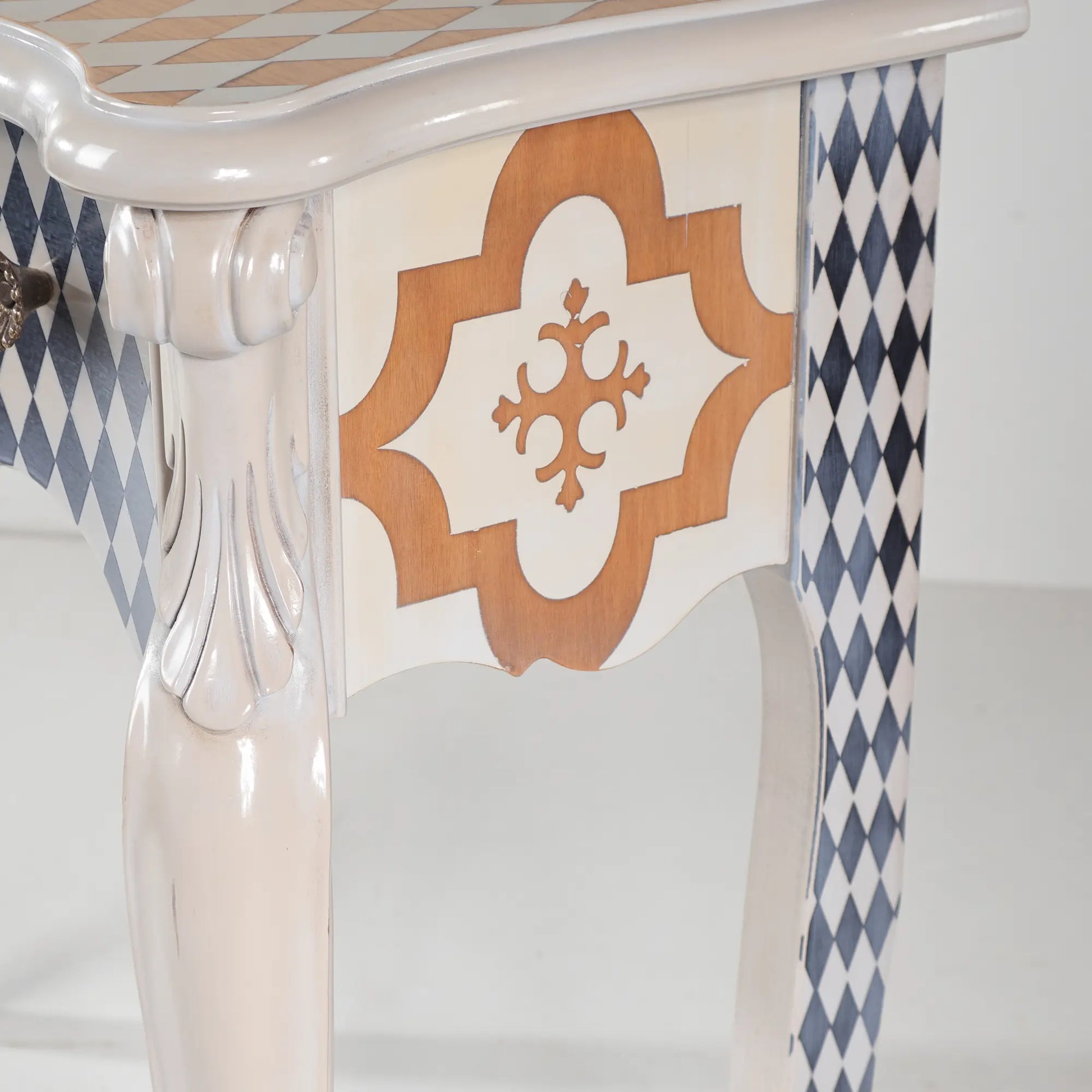 Detalle lateral de la Consola Vita con pata curva, talla ornamental y motivo geométrico.