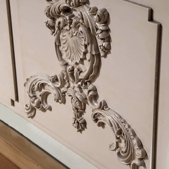 Detalle tallado ornamental del cabecero Utopía realizado en madera lacada.