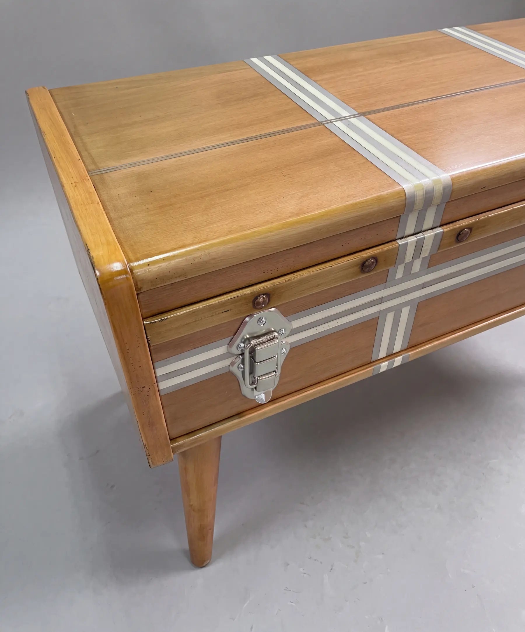 Detalle de la mesa de centro Suitcase con herrajes metálicos y líneas decorativas.