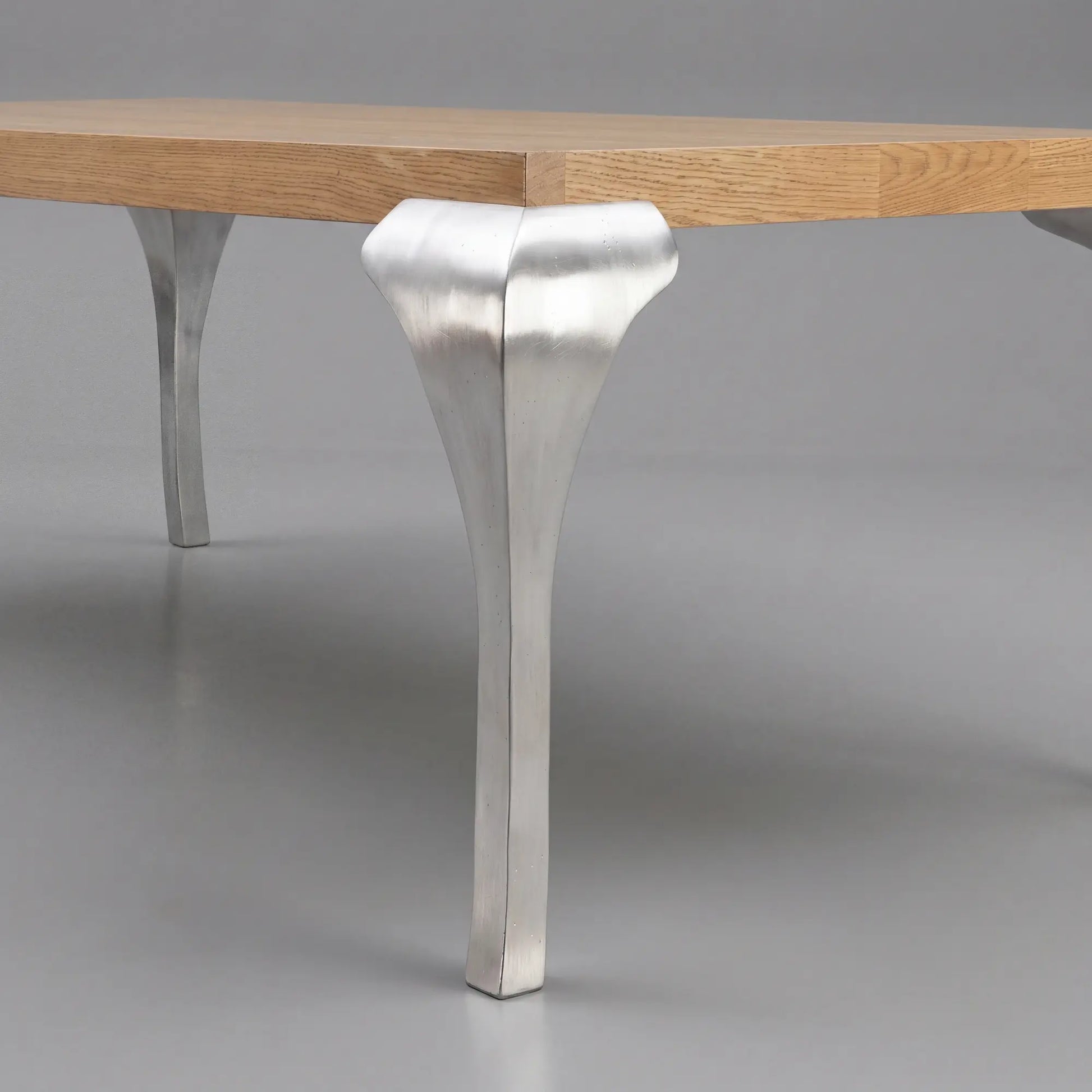 Detalle de pata metálica escultórica de la mesa de comedor Manila con sobre de madera
