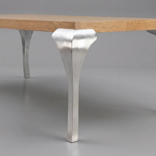 Detalle de pata metálica escultórica de la mesa de comedor Manila con sobre de madera