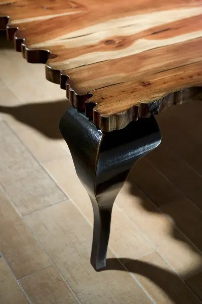 Detalle del tablero de madera irregular y pata negra curva de la mesa de centro Charol