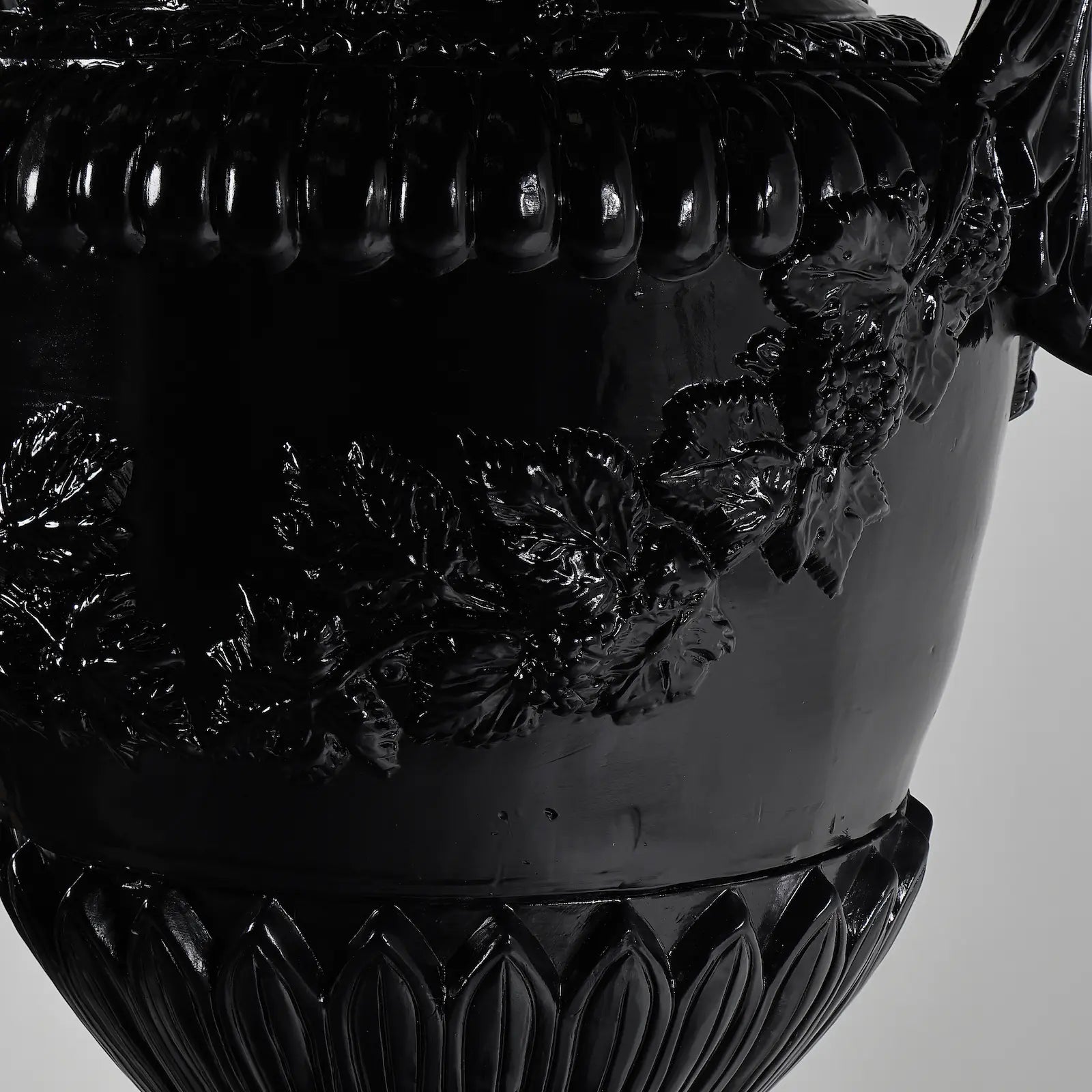 Detalle de relieves florales y guirnaldas del Jarrón Versailles en negro brillante.