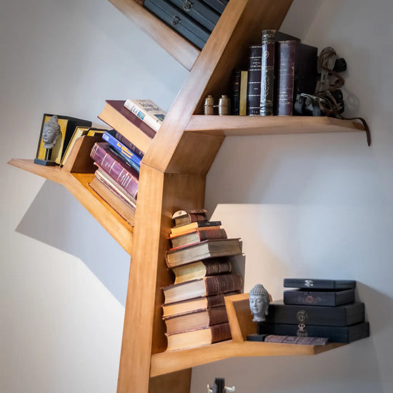 Detalle de las baldas inclinadas del librero Tree vertical con libros y objetos decorativos.