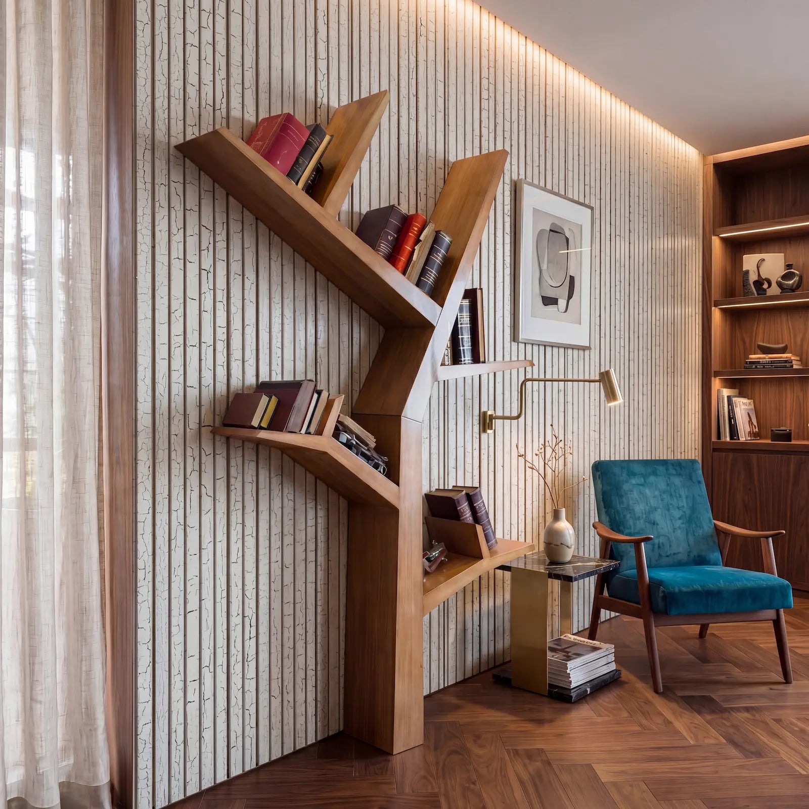 Estantería Tree vertical de diseño en tono madera integrada en una zona de lectura elegante.