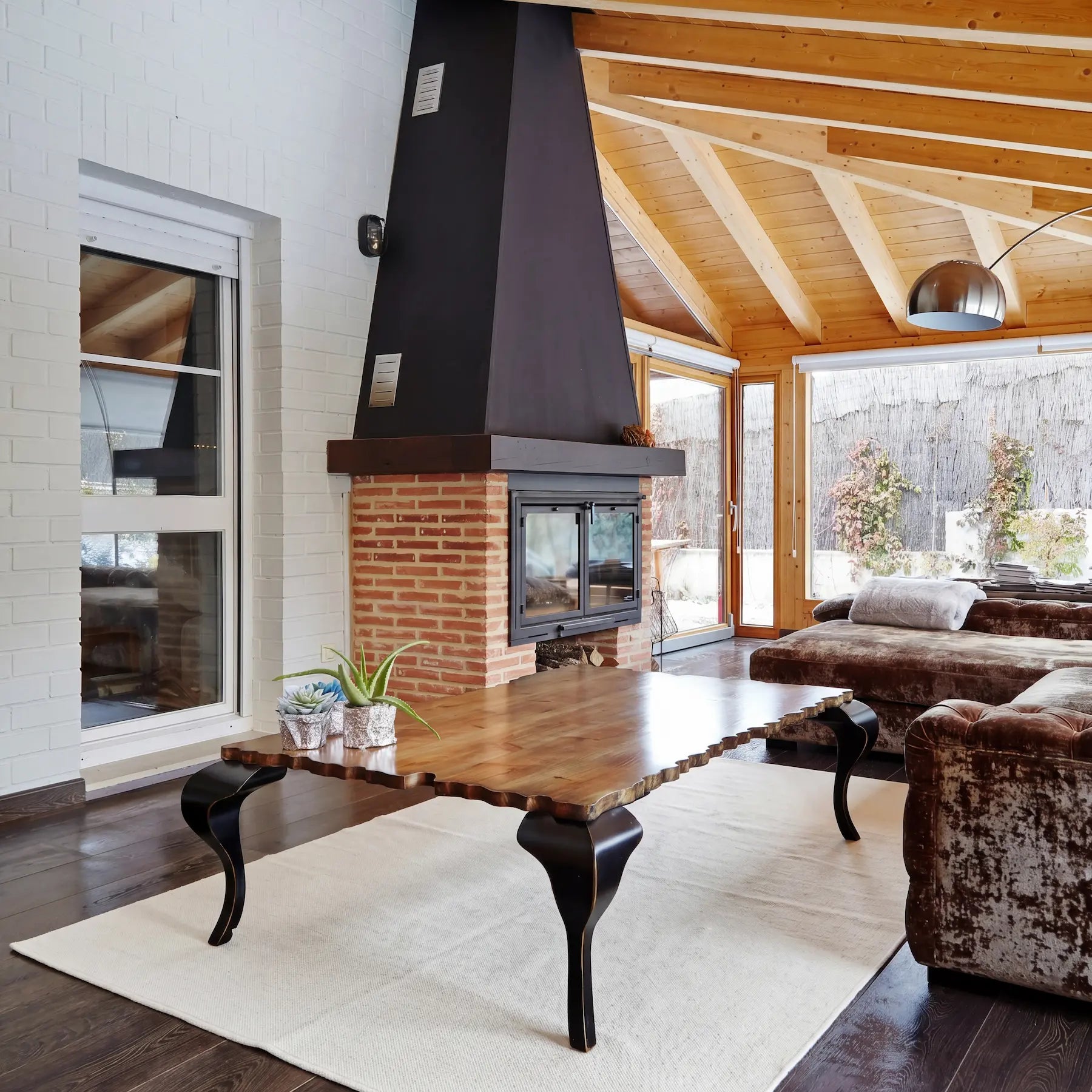 Mesa de centro de diseño Charol en madera natural con patas negras en un salón con chimenea