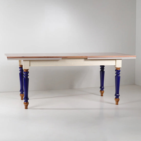 Mesa de comedor extensible Cascabella vista frontal con patas torneadas en azul cobalto.