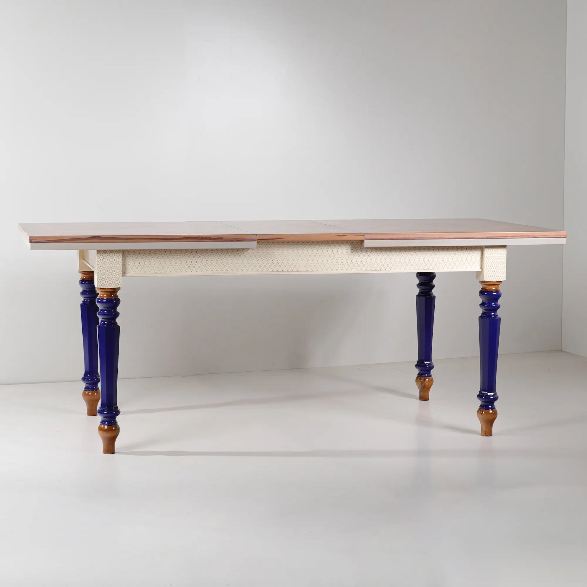 Mesa de comedor extensible Cascabella vista frontal con patas torneadas en azul cobalto.