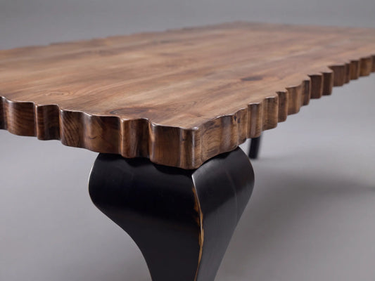 Detalle de la Mesa Charol con sobre de madera tallado y pata negra curva