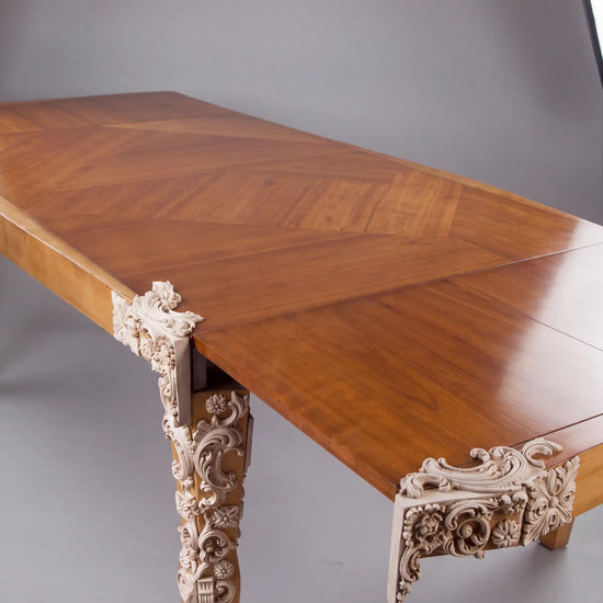 Detalle de la Mesa Cubista de madera con talla ornamental blanca en una esquina