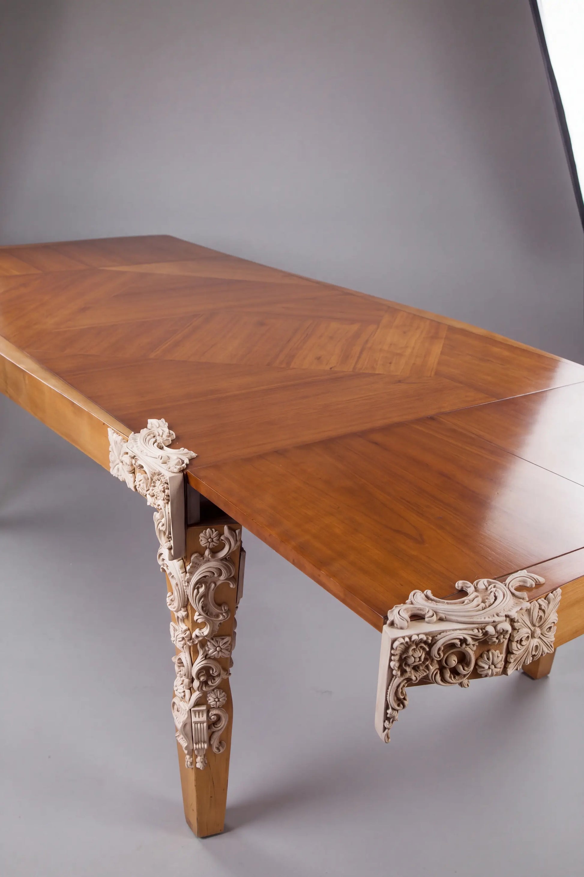 Detalle de la Mesa Cubista de madera con talla ornamental blanca en una esquina