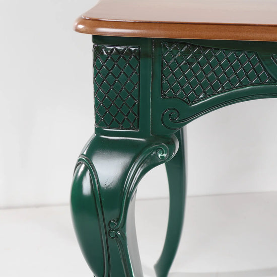 Detalle de la pata curva y el faldón ornamental verde de la mesa Dafoe.