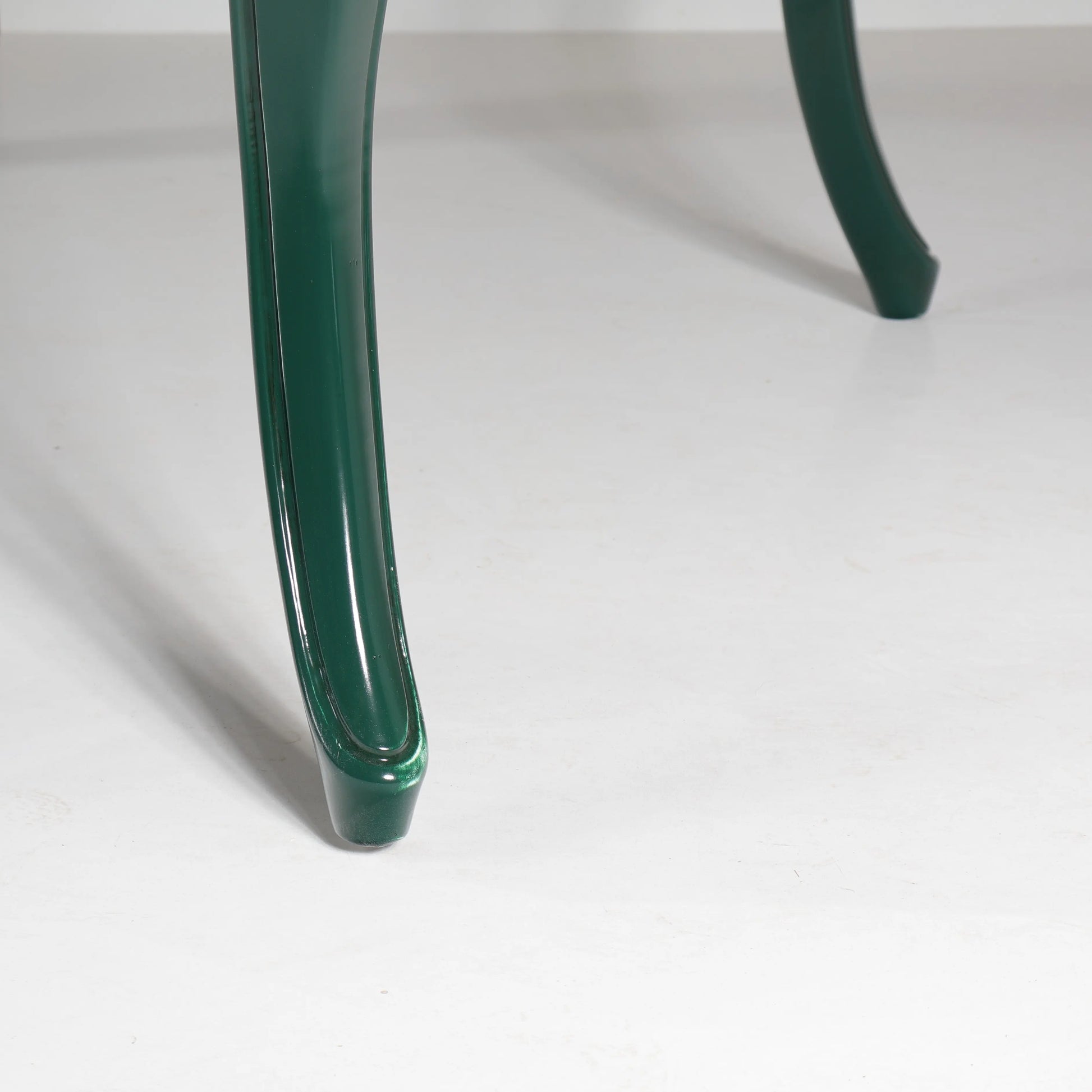 Detalle de una de las estilizadas patas curvas verdes de la mesa de comedor Dafoe.