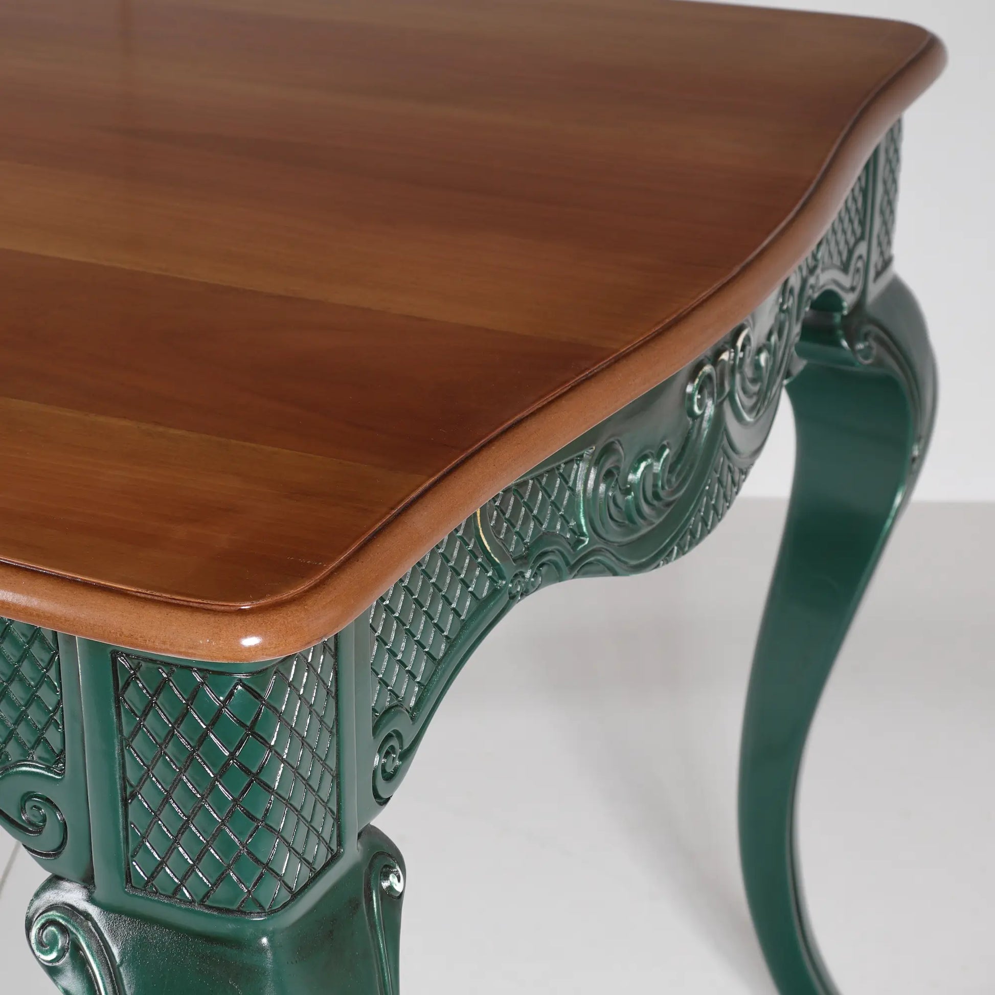 Detalle del sobre en tono madera y la estructura ornamentada verde de la mesa Dafoe.