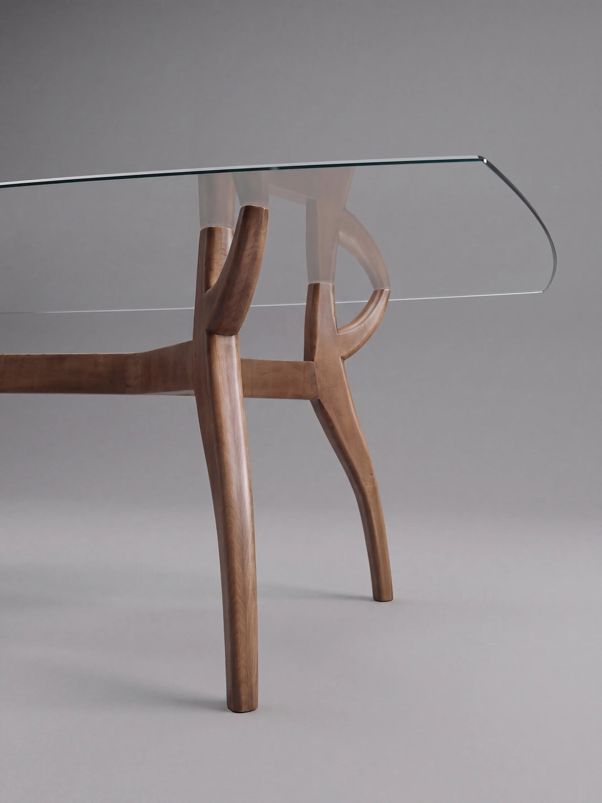 Patas curvas de madera de la Mesa Irati con tapa rectangular de cristal transparente