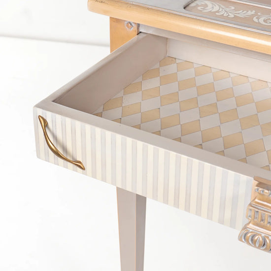 Cajón abierto de la mesa de juegos Kapello con interior decorado mediante un patrón geométrico.