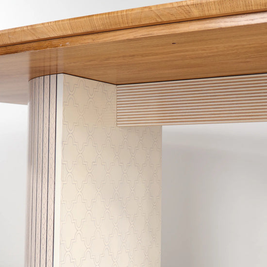 Detalle de la Mesa Moon con sobre en tono madera y base clara decorada con motivos geométricos.