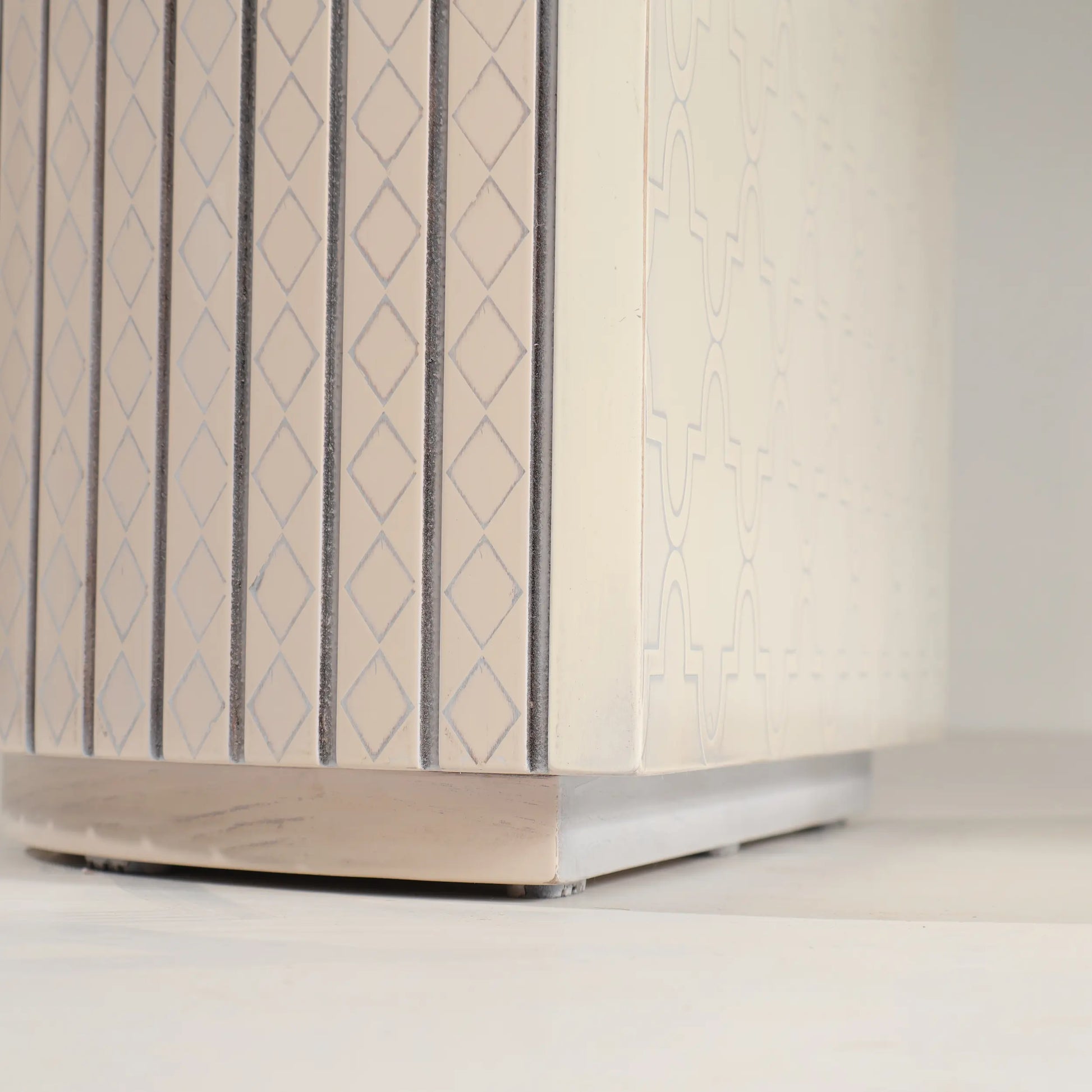 Detalle del pedestal de la Mesa Moon con líneas verticales, rombos y ornamentación gráfica.