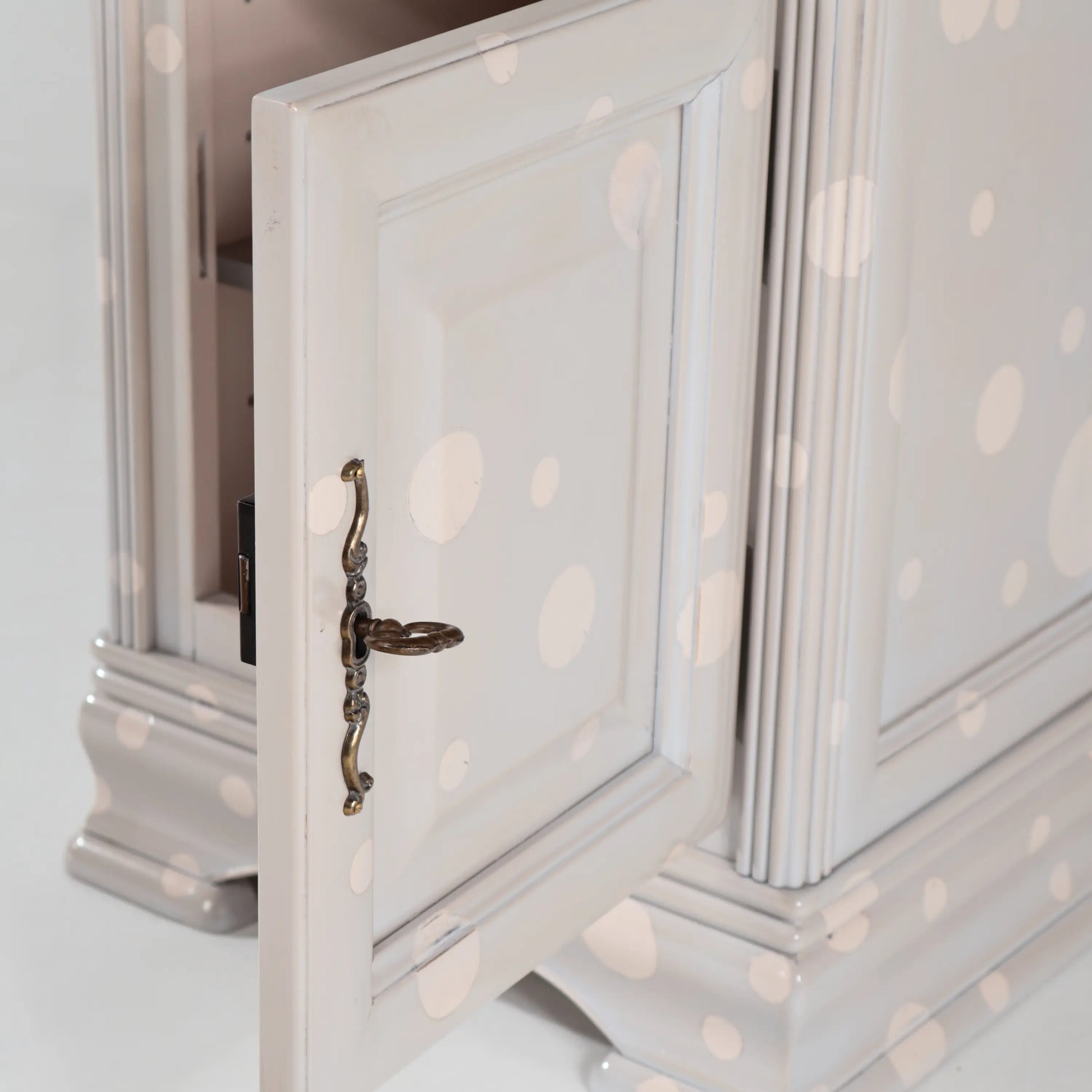 Puerta abierta de la mesilla Giuletta con molduras y tirador de estilo clásico.