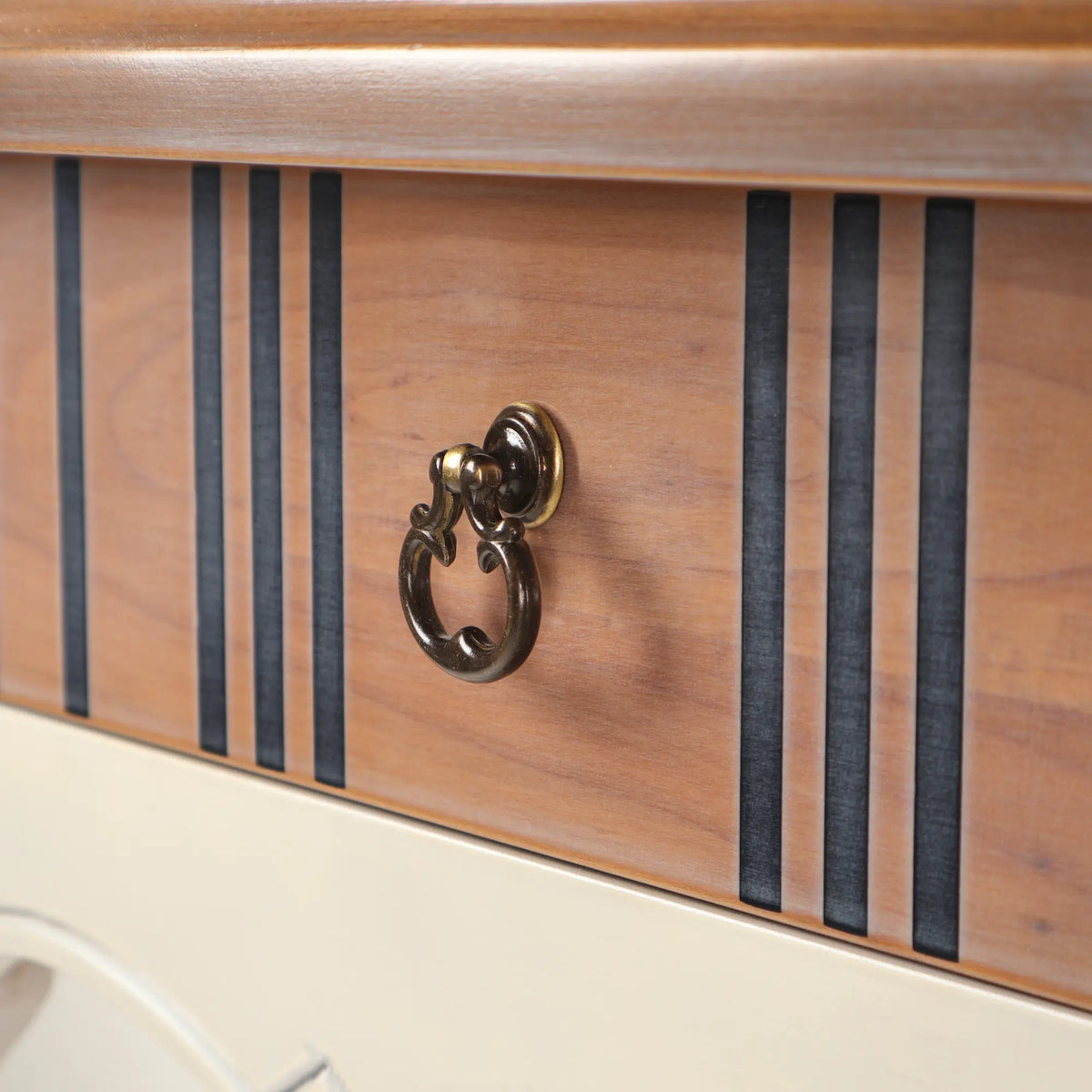 Detalle del cajón de la mesita Fini con líneas verticales oscuras y faldón decorativo.