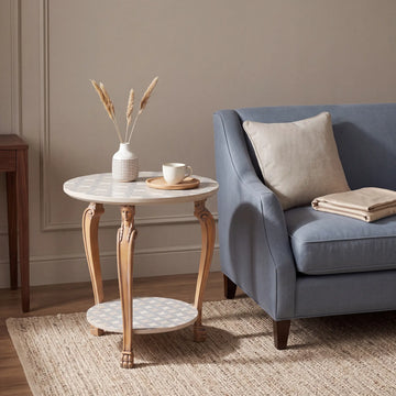 Mesita Olise junto a un sillón azul en un salón elegante de tonos neutros.