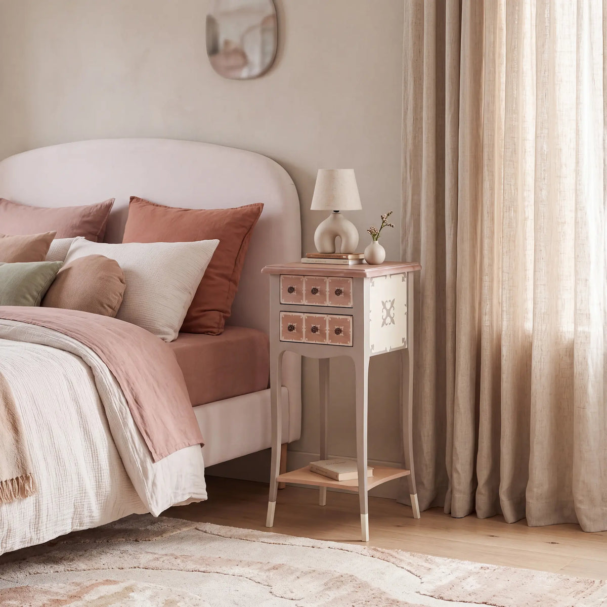 Mesita de noche Rubic de Lola Glamour junto a una cama tapizada en un dormitorio de tonos suaves.