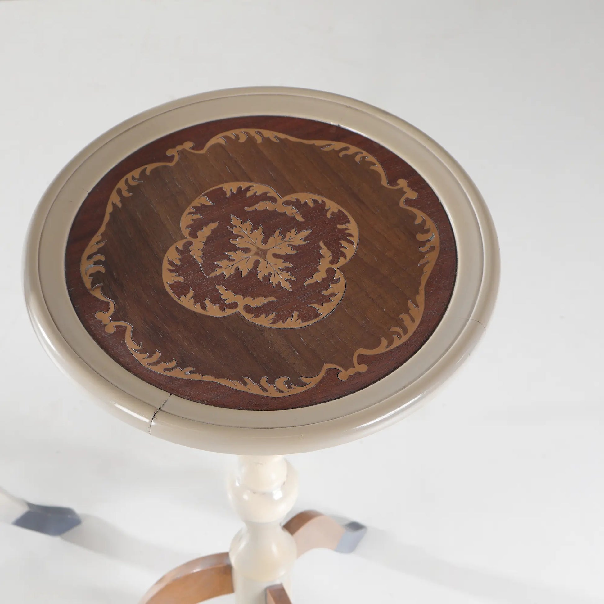 Detalle del sobre redondo de la mesita Siena con composición ornamental en tonos madera