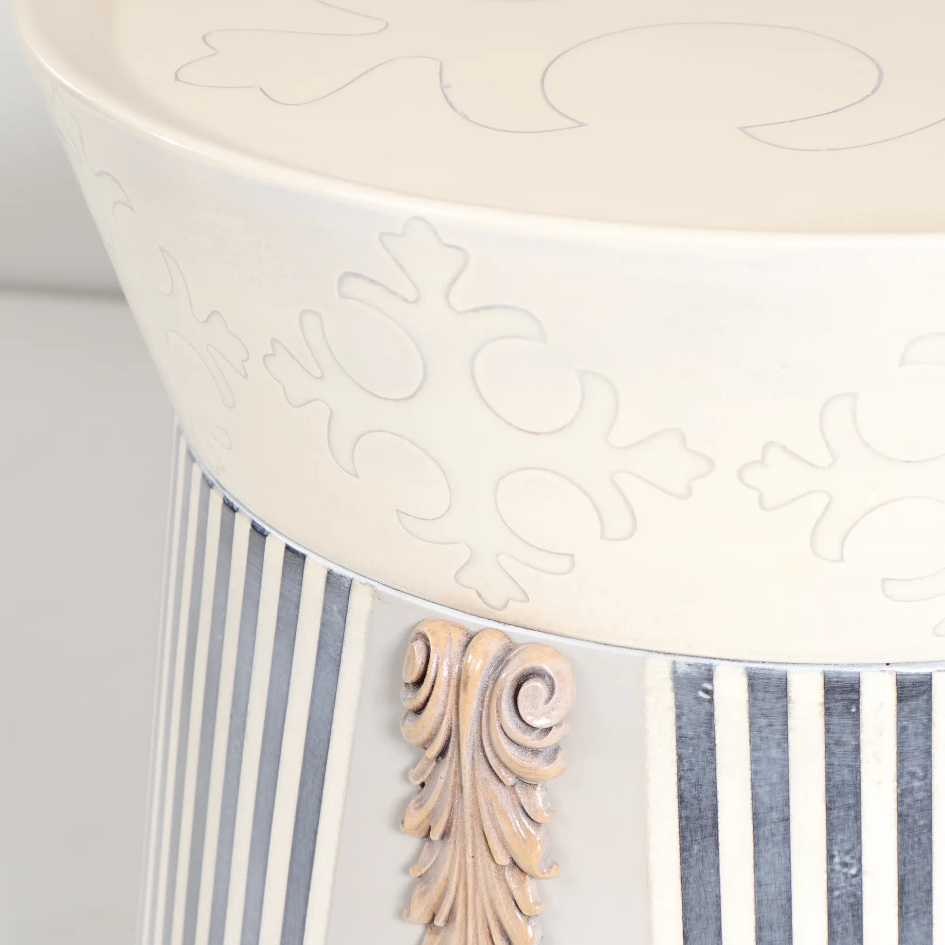 Detalle de la Mesita Tambor con friso decorativo, rayas verticales y aplique ornamental.