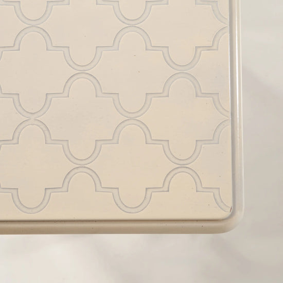 Detalle del sobre intermedio de las Mesitas Tris con dibujo ornamental repetido en crema
