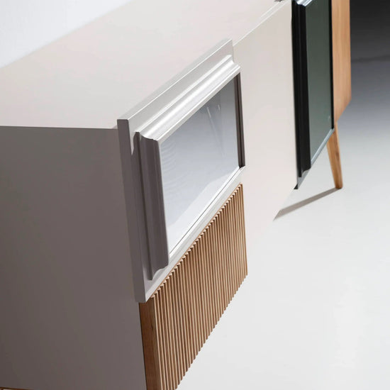 Detalle lateral del Mueble de TV Uka con volúmenes asimétricos, patas torneadas y frentes moldurados.