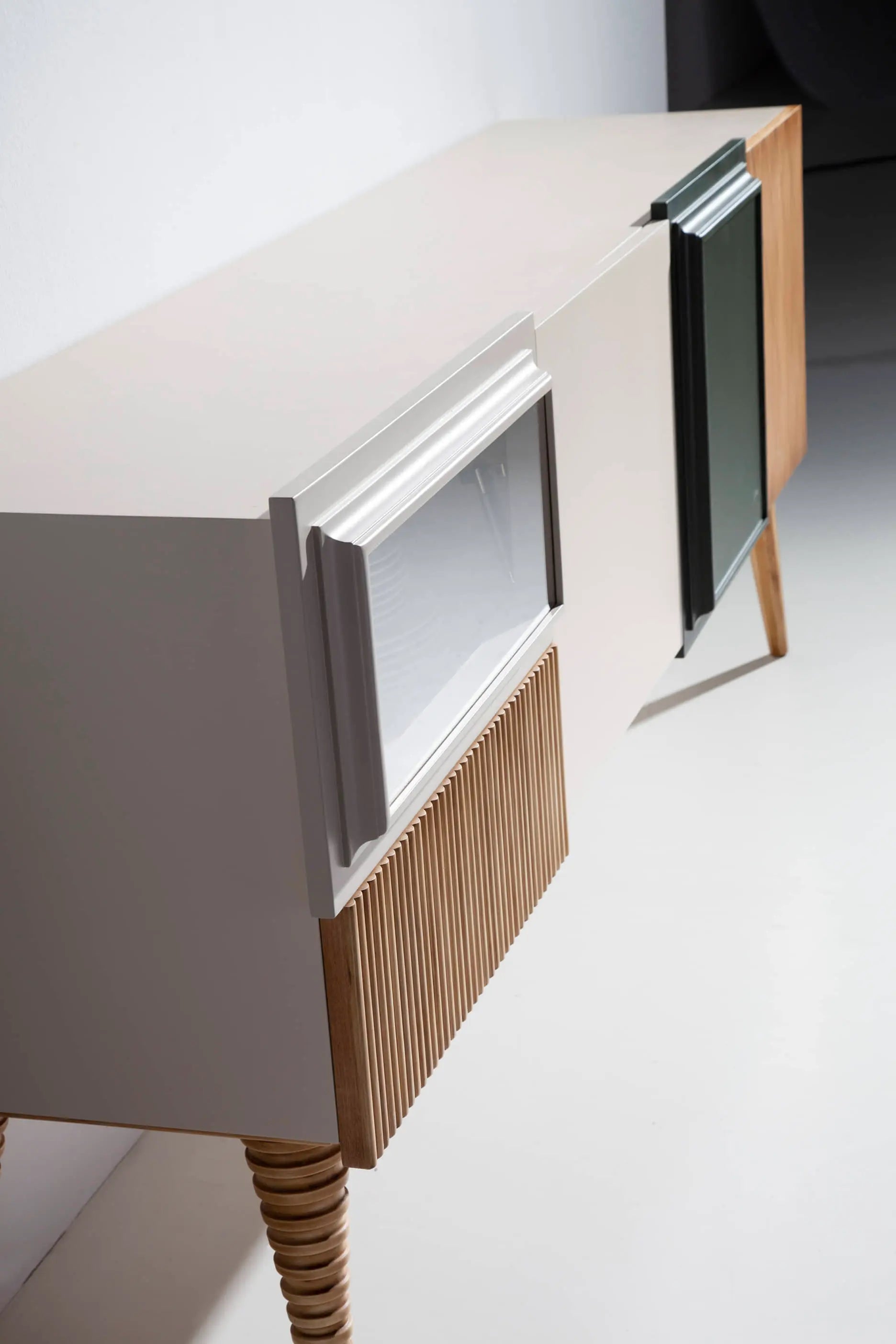 Detalle lateral del Mueble de TV Uka con volúmenes asimétricos, patas torneadas y frentes moldurados.