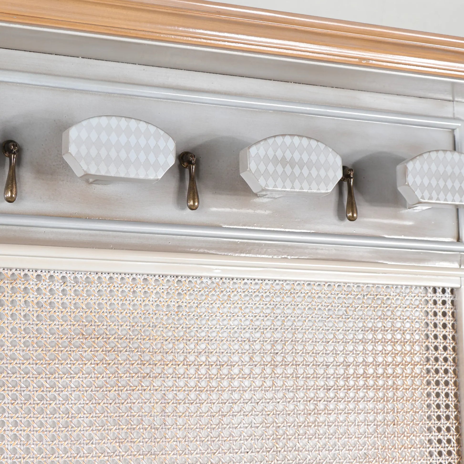 Detalle de los colgadores del Perchero Rejilla con acabado claro, tiradores decorativos y panel de rejilla.