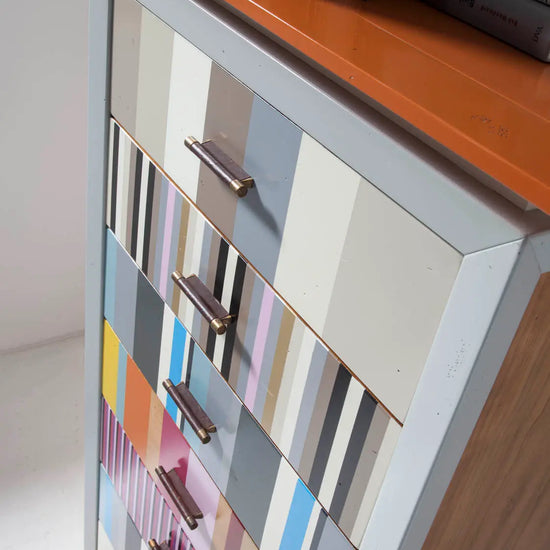 Detalle superior del Sinfonier Ada con cajones de colores, sobre naranja y lateral de madera